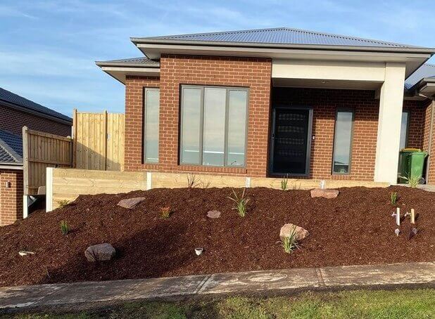 A timber retaining wall with steel sleepers and a tanbark garden with a letterbox.