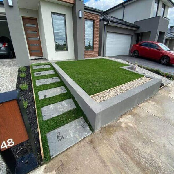 A rendered block retaining wall with artificial grass and bluestone pavers at a Melbourne property.